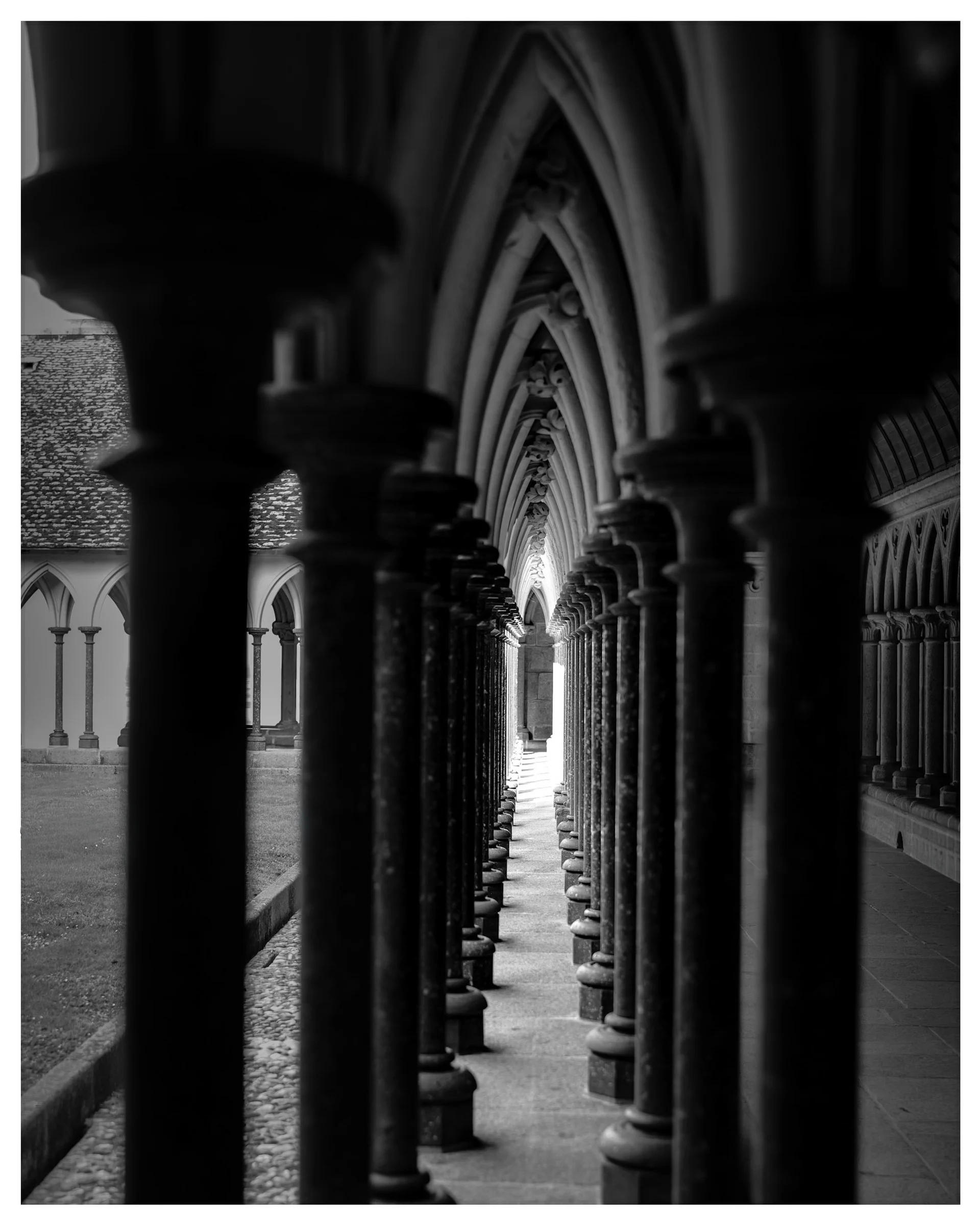 Black and white photo of Gothic cloister arches and columns at Mont-Saint-Michel